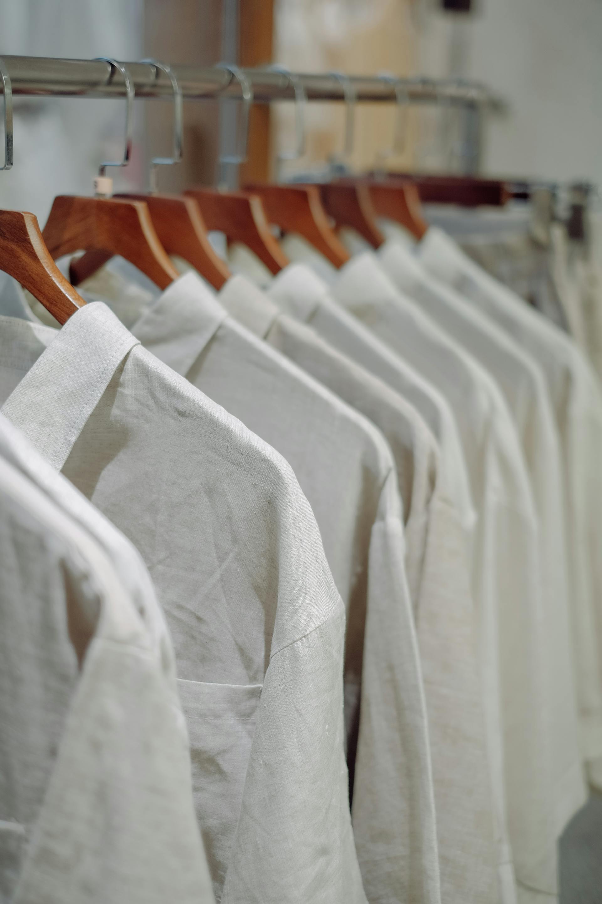 Row of white woven shirts on wooden hangers